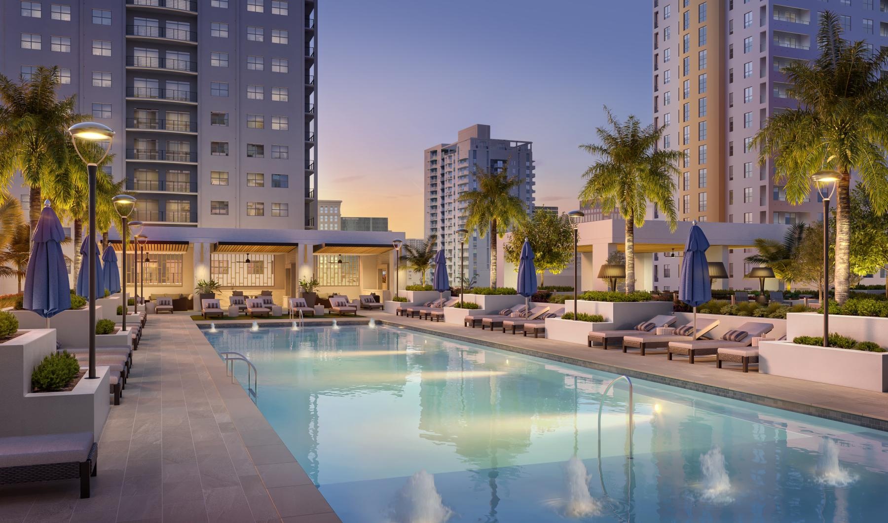 a pool with lounge chairs and umbrellas by a building