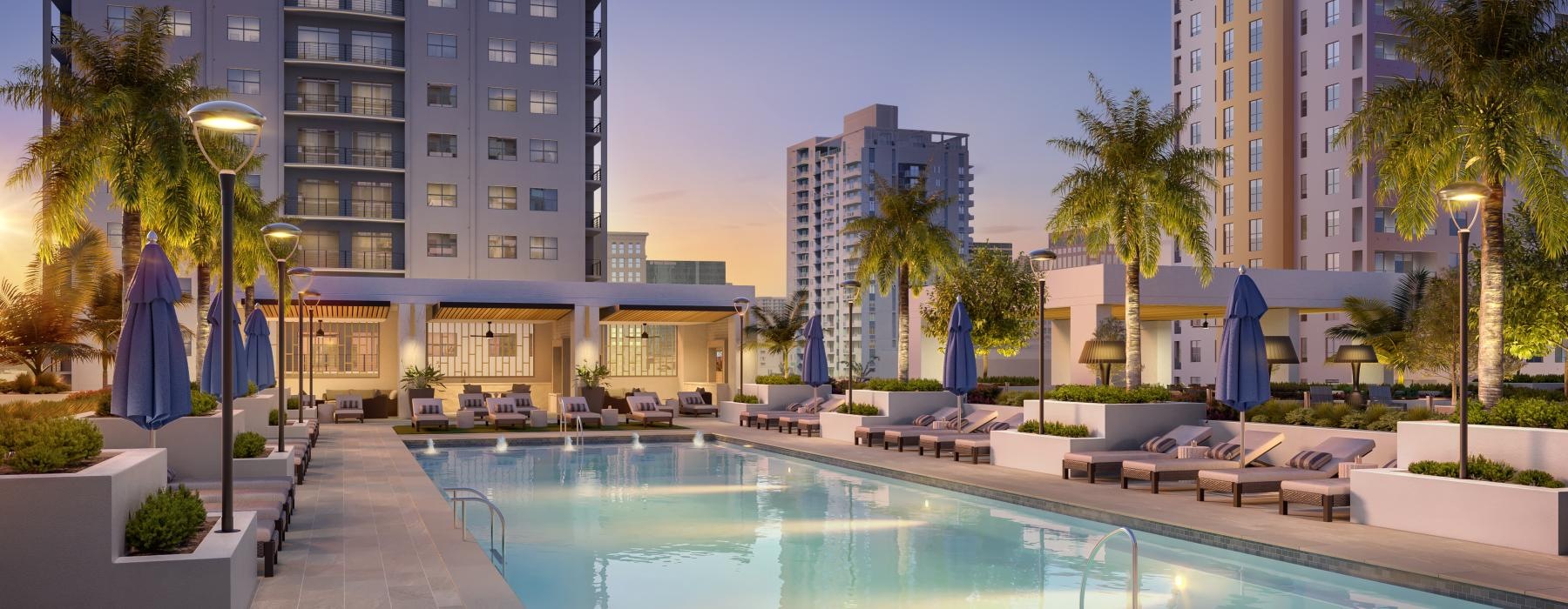 a pool with lounge chairs and umbrellas by a building